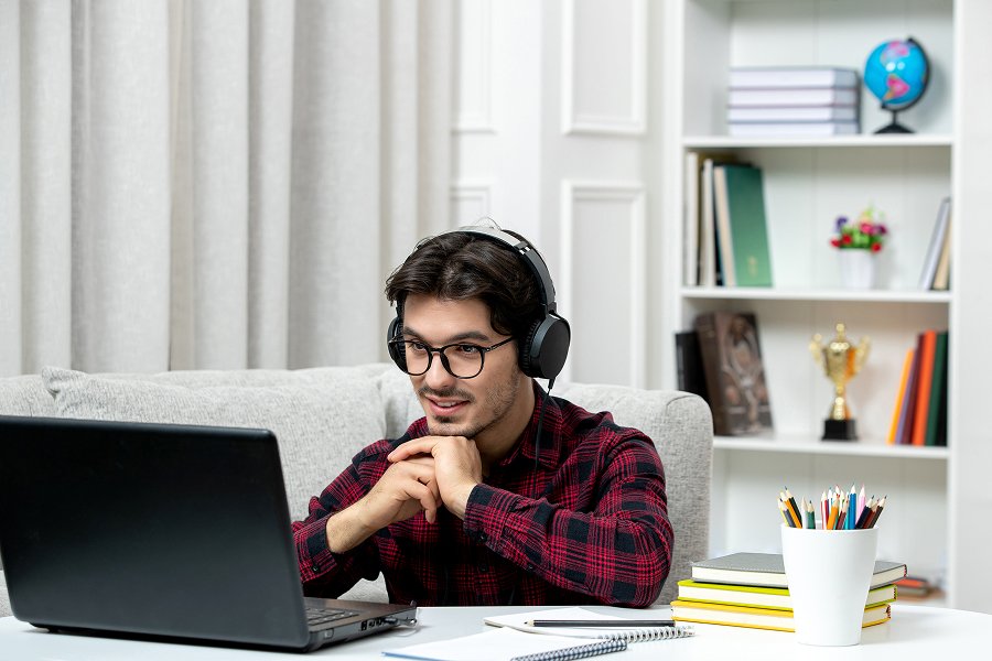 Man in headphones smiling at his laptop during a video call